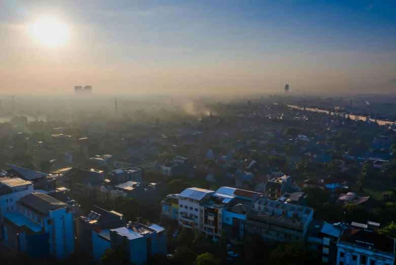 a view of a city from the top of a building, by Daniel Lieske, happening, morning haze, indonesia, early morning sun in the sky, drone photograpghy