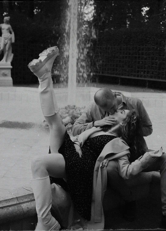 a black and white photo of a couple kissing in front of a fountain, by Cherryl Fountain, figuration libre, embarrassing, legs intertwined, dasha taran, silly