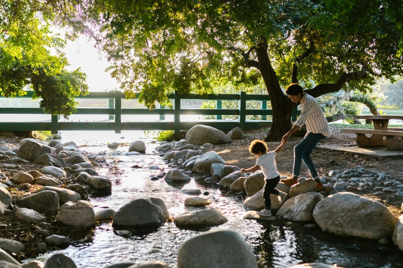 a man and a little girl crossing a stream, unsplash, interactive art, hollister ranch, garden pond scene, parks and public space, landscape architecture photo