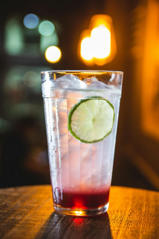 a drink sitting on top of a wooden table, by Austin English, sparkling water, crimson, at a bar, thumbnail