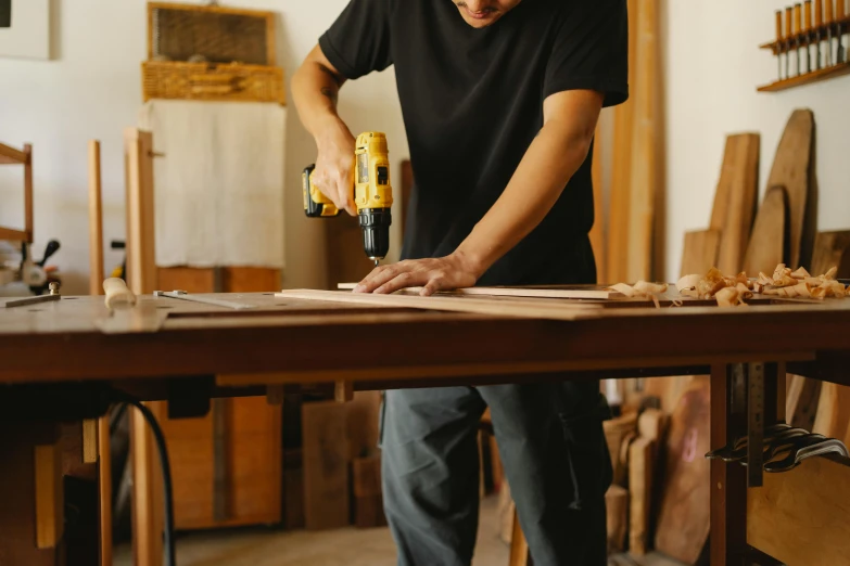 a man using a power drill to cut a piece of wood, pexels contest winner, arbeitsrat für kunst, wooden tables, full body image, 1 4 9 3, designer product