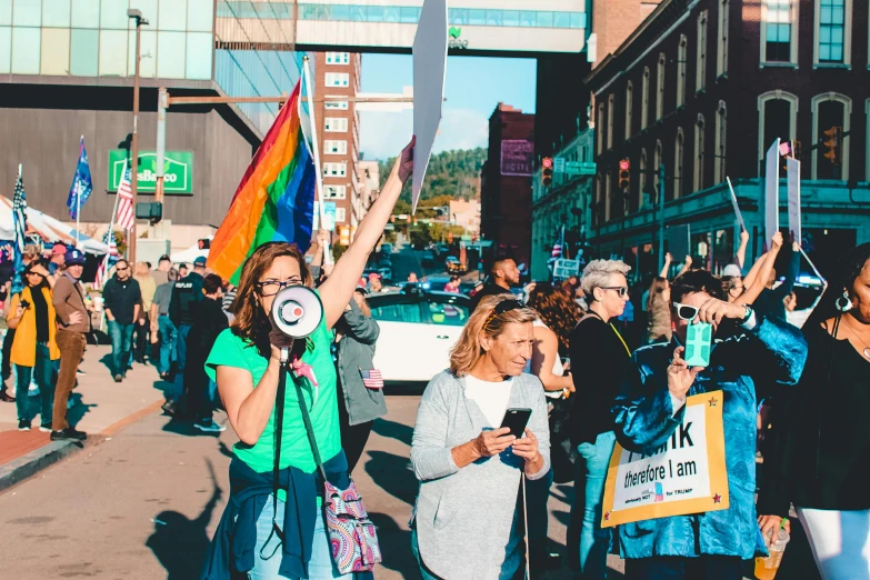 a group of people walking down a street holding flags, a photo, by Julia Pishtar, pexels, lesbian, woman his holding a sign, minn, alexis franklin