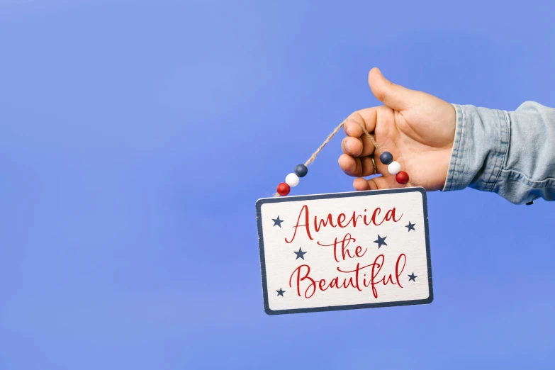 a person holding a sign that says america the beautiful, background image, decorations, full product shot, with a blue background