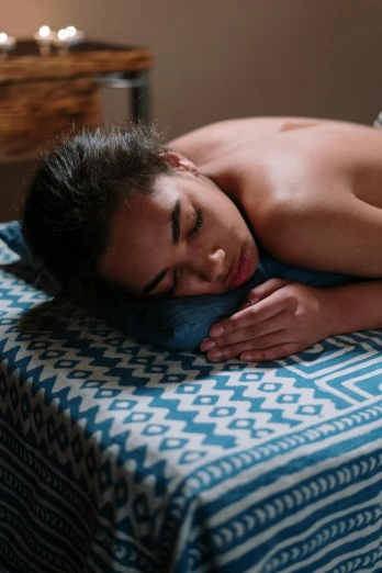 a woman getting a back massage at a spa, a portrait, by Jessie Algie, pexels contest winner, resting on a pillow, maori, blue, asleep