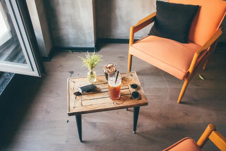 an orange chair sitting next to a wooden table, trending on unsplash, cold brew coffee ), wooden coffee table, high angle, multiple stories