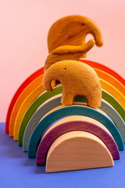 a wooden elephant standing on top of a rainbow, by Helen Stevenson, carefully designed, arches, close up, different sizes