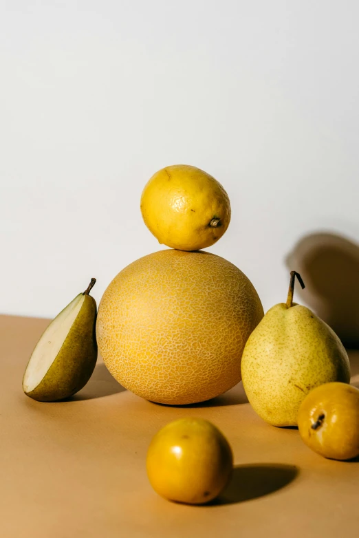 a pile of fruit sitting on top of a table, a still life, trending on pexels, big pear-shaped head, light yellow, spherical body, detailed product shot