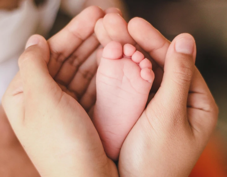 a woman holding a baby's foot in her hands, pexels, avatar image, group photo, high-resolution, fan favorite