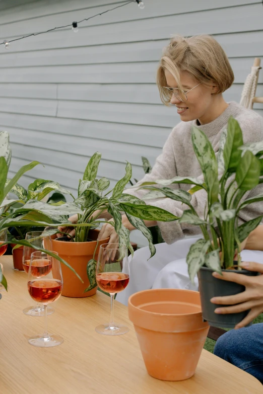 a group of people sitting around a table with plants, premium quality, holding a drink, zoomed in, large potted plant