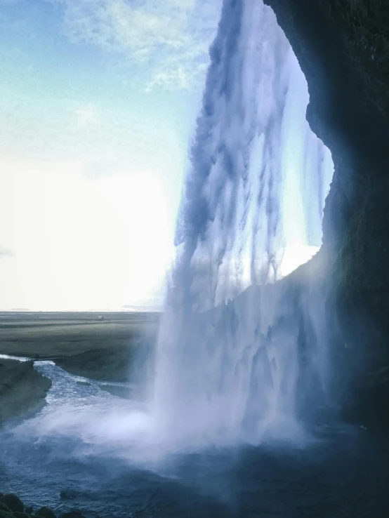 a person standing in front of a waterfall, by Hallsteinn Sigurðsson, pexels contest winner, surrealism, 1960s color photograph, massive arch, 1987 photograph, overexposed photograph