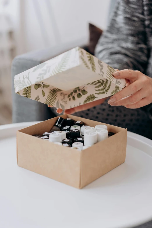 a woman opening a gift box on a table, by Eden Box, vials, botanical herbarium paper, thumbnail, white box