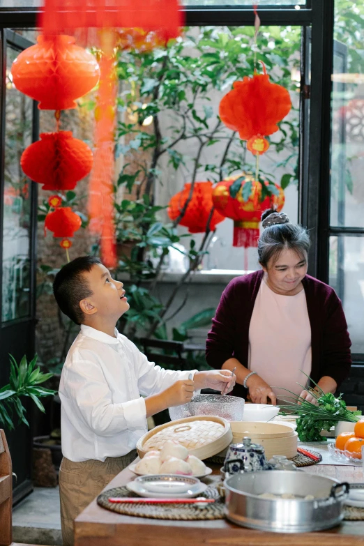 a group of people standing around a table with food, wearing a red cheongsam, hanging lanterns, cooking, profile image