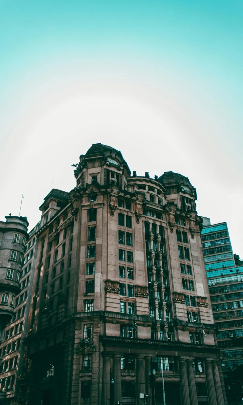 a tall building sitting in the middle of a city, by IAN SPRIGGS, pexels contest winner, art nouveau, neo-classicism, faded colors, neo - andean architecture, round-cropped