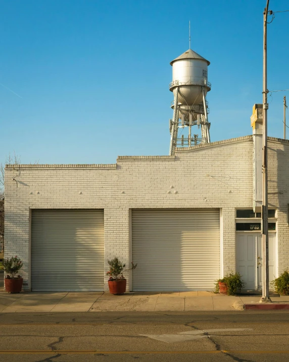 a white building with a water tower in the background, by Carey Morris, los angelos, garage, no cropping, photo for a store