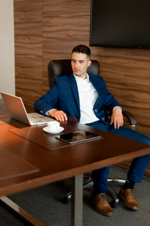 a man sitting at a desk in front of a laptop computer, trending on pexels, renaissance, stylish suit, f 1 driver charles leclerc, sitting on an armchair, hip corporate