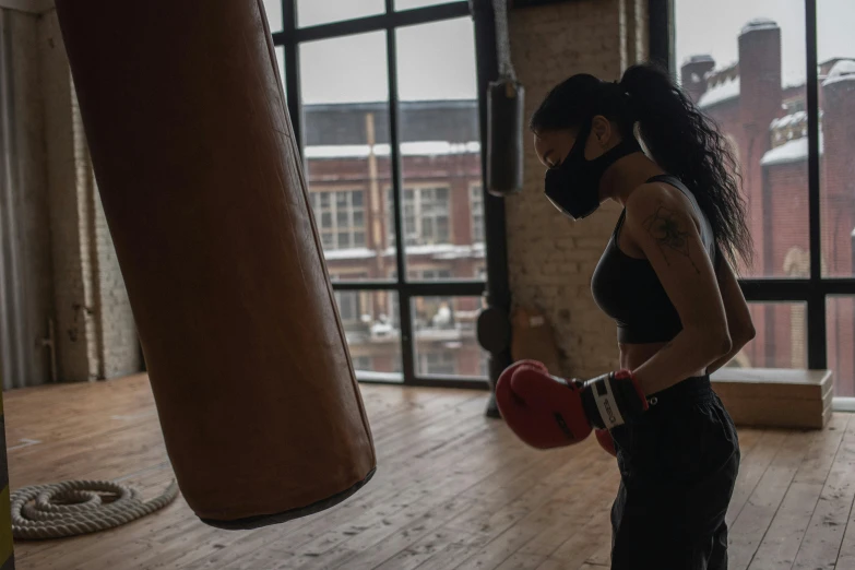 a woman standing next to a punching bag, pexels contest winner, mask off, action with run and fight, profile image, thumbnail