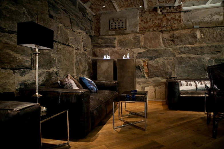 a living room filled with furniture and a stone wall, by Eero Snellman, unsplash, romanesque, in a basement, minna sundberg, opposite the lift-shaft, slate