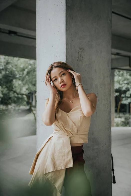 a woman leaning against a pillar talking on a cell phone, a picture, inspired by Ruth Jên, trending on pexels, renaissance, wearing crop top, neutral pose, manila, wind - swept