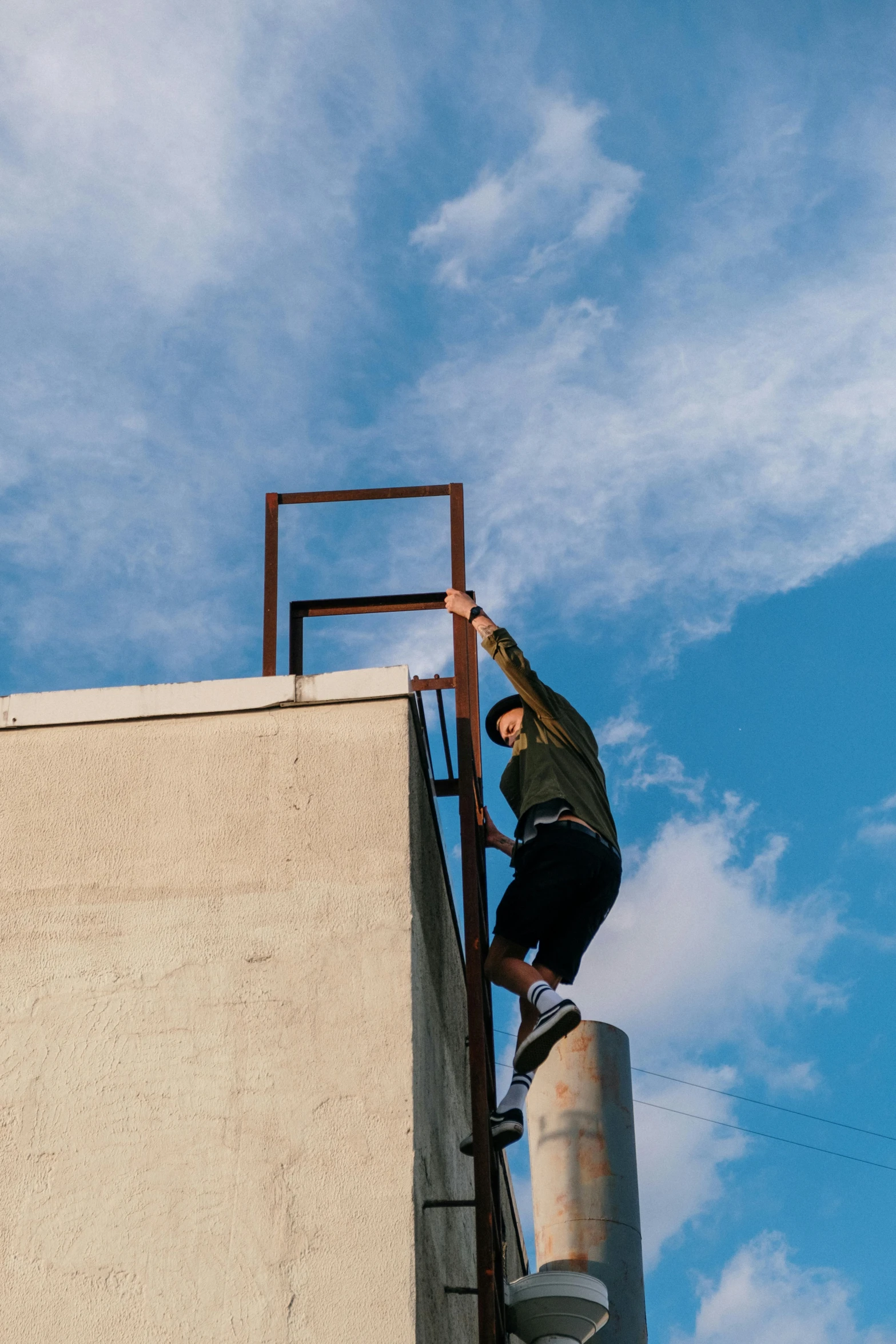 a man riding a skateboard up the side of a building, by Niko Henrichon, unsplash, conceptual art, blue sky, scaffolding collapsing, parkour, creating a thin monolith