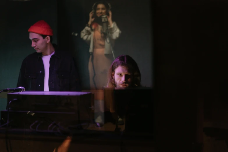 a couple of people that are sitting in front of a keyboard, a portrait, by Tom Bonson, unsplash, realism, performing on stage, in the backrooms, reflection, neil blevins and jordan grimmer