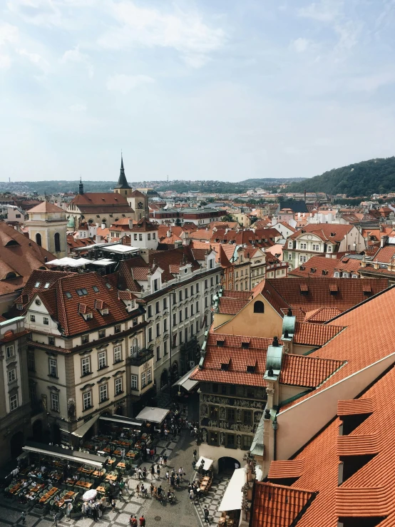 a view of a city from the top of a building, by Emma Andijewska, prague in the background, orange roof, square, low quality photo