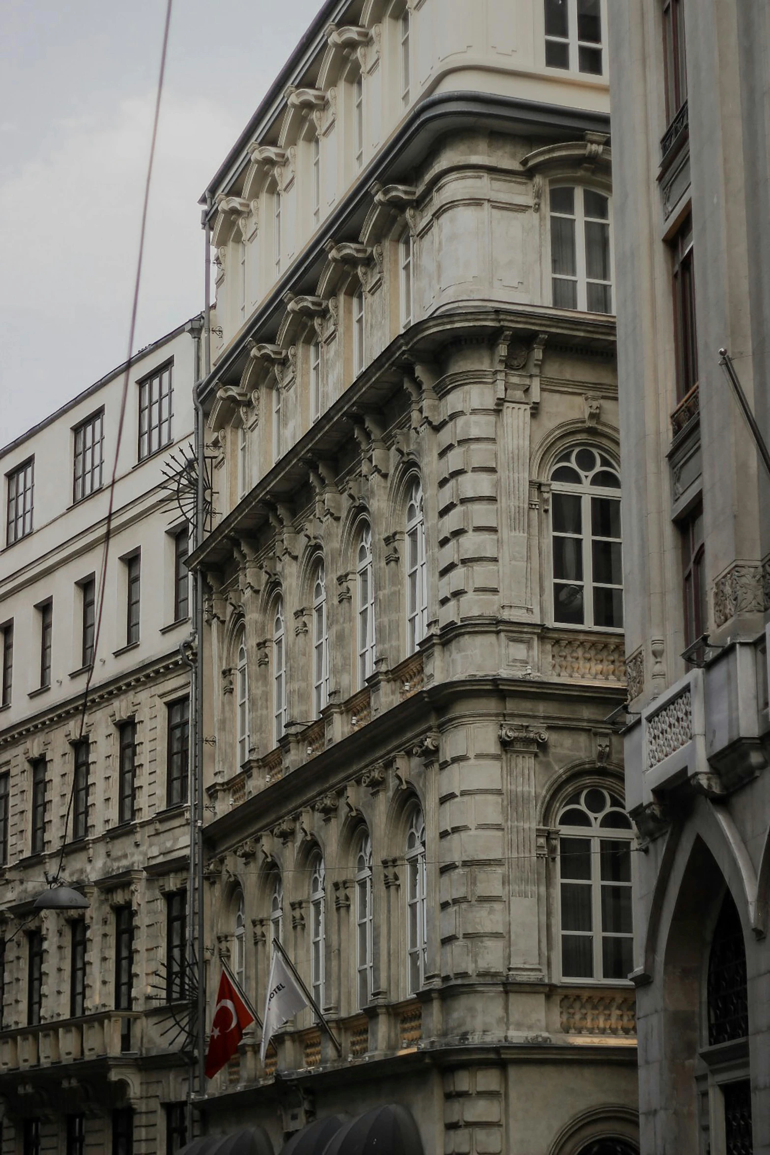 a group of people walking down a street next to tall buildings, a photo, inspired by Mihály Munkácsy, baroque, stone facade, close up shot from the side, ornamentation, savannah