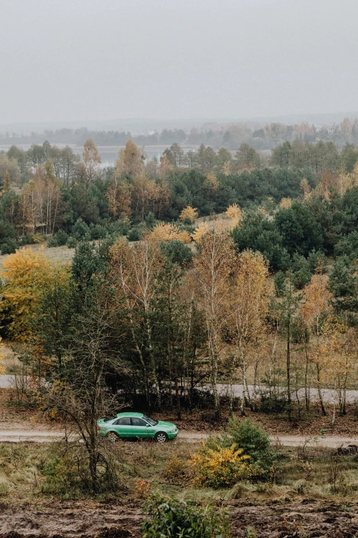 a green car driving down a dirt road, inspired by Elsa Bleda, unsplash, visual art, pripyat, panorama distant view, during autumn, 15081959 21121991 01012000 4k