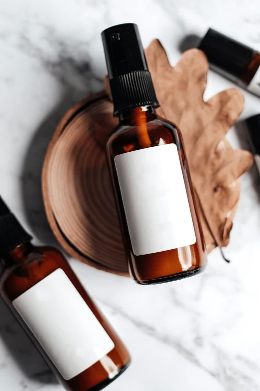 three bottles of essential oils on a marble surface, a picture, by Robbie Trevino, trending on pexels, brown hair in a ponytail, thumbnail, handcrafted, monochrome