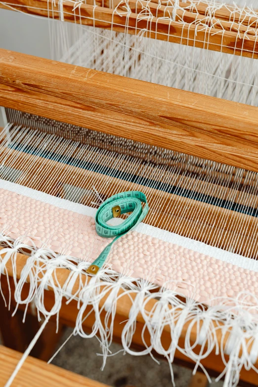 a close up of a weaving machine on a table, arts and crafts movement, pink white turquoise, natural materials, corduroy, jewelry