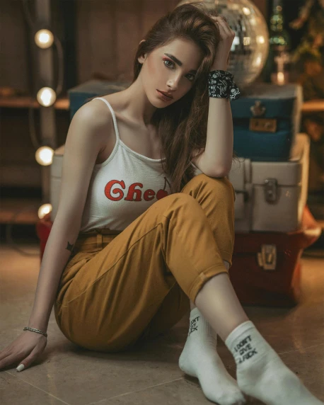a woman sitting on the floor next to a pile of luggage, a colorized photo, inspired by Elsa Bleda, trending on pexels, white! tank top with a print, beautiful androgynous girl, yellow and red, girl cute-fine-face