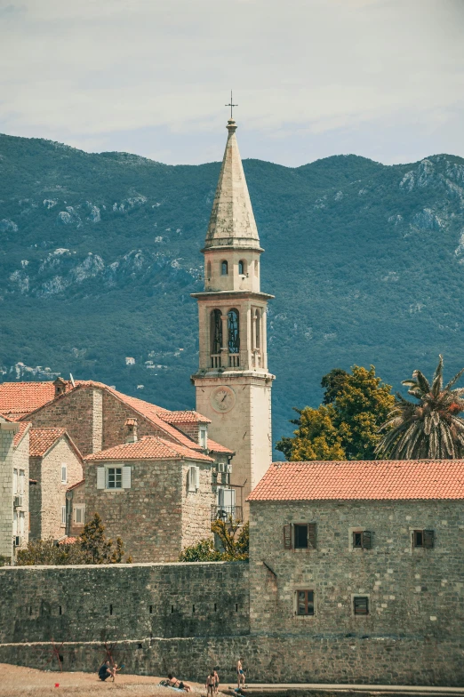 a clock tower on top of a building next to a body of water, romanesque, boka, tiled roofs, city views