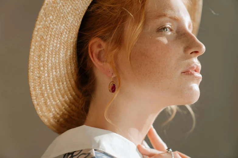 a close up of a person wearing a hat, by Emma Andijewska, trending on pexels, renaissance, long earrings, ( redhead, rubies, summer light