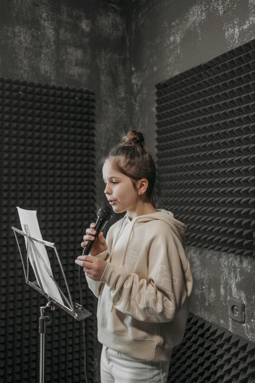 a woman standing in front of a microphone in a recording studio, by artist, pexels, girl wearing hoodie, kid, gif, cardboard