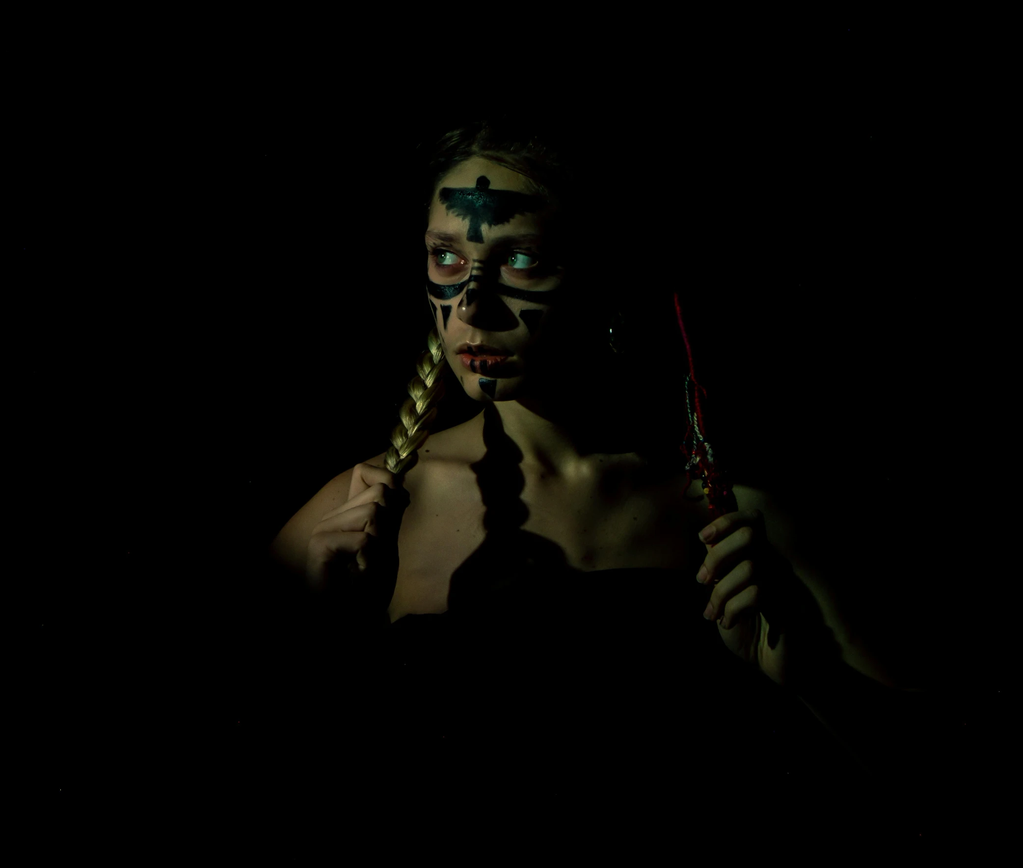 a woman holding a pair of scissors in front of her face, an album cover, by Kristian Zahrtmann, pexels contest winner, antipodeans, tribal facepaint, warrior fighting in a dark scene, glowing in the dark, wearing a native american choker