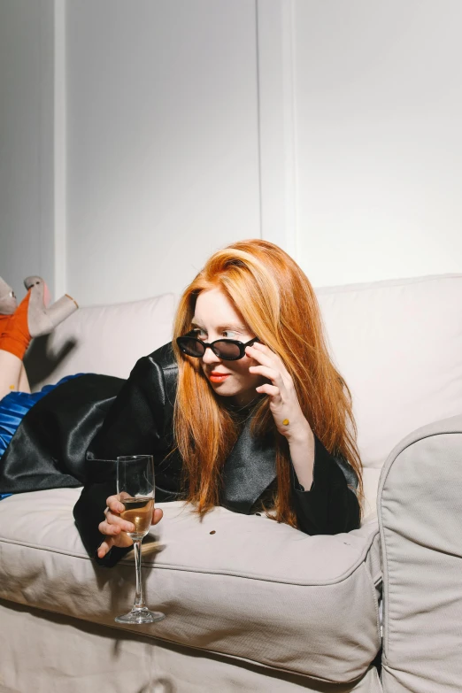 a woman laying on a couch with a glass of wine, an album cover, very long orange hair, in style of ren hang, karen gillan, 2019 trending photo