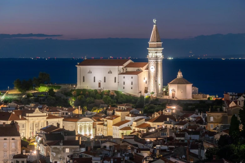 a large white building sitting on top of a lush green hillside, by Adam Marczyński, unsplash contest winner, romanticism, venice at dusk, croatian coastline, church in the background, square