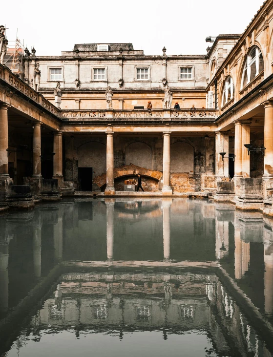 a reflection of a building in a pool of water, roman bath, unsplash photography, multiple stories, a wide open courtyard in an epic