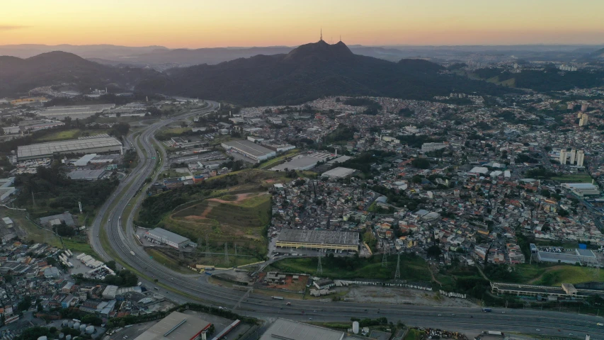 an aerial view of a city at sunset, a matte painting, by Breyten Breytenbach, pexels contest winner, são paulo, distant town in valley and hills, industrial surrounding, grey