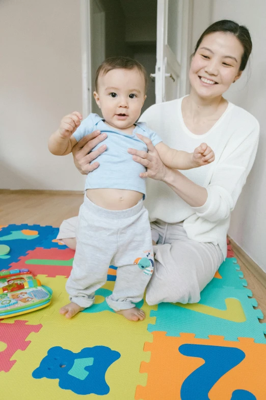 a woman sitting on the floor with a baby, a picture, standing posture, playful and cheerful, half-body, for kids