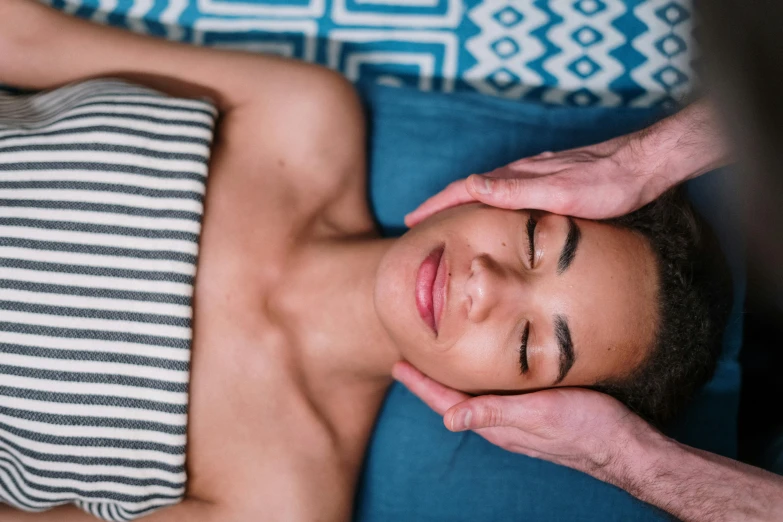 a woman getting a head massage at a spa, by Julia Pishtar, trending on pexels, jordan peele's face, graphic print, laying in bed, coloured photo