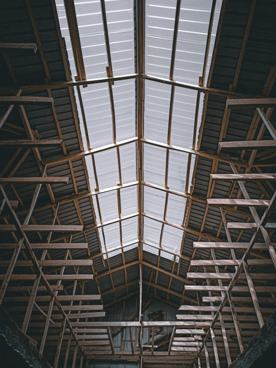 the inside of a building with a skylight, an album cover, unsplash contest winner, peaked wooden roofs, scaffolding, trending on vsco, hangar