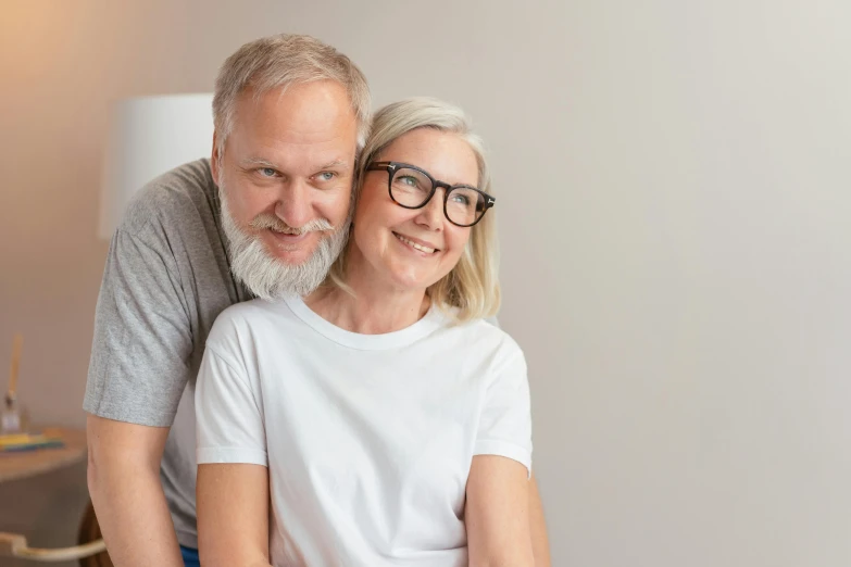 a man and a woman sitting on top of a bed, short white beard, medical photography, man with glasses, happy couple