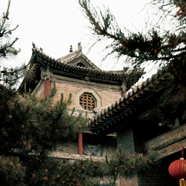 a tall building with a red lantern hanging from it's roof, inspired by Wu Daozi, in avila pinewood, photograph taken in 1989, with great domes and arches, brown