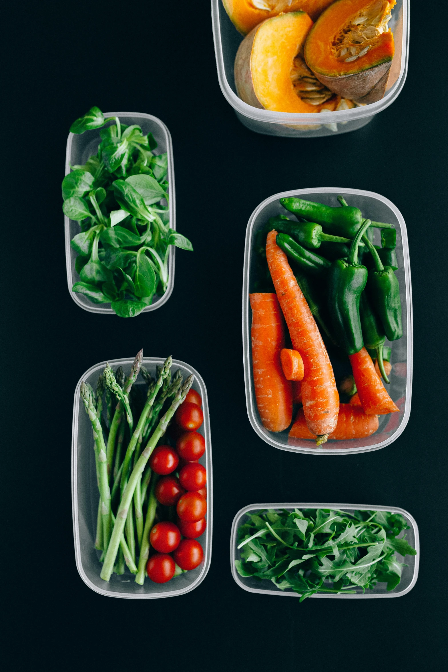 a group of plastic containers filled with different types of vegetables, with a black background, lush greens, flatlay, ignant