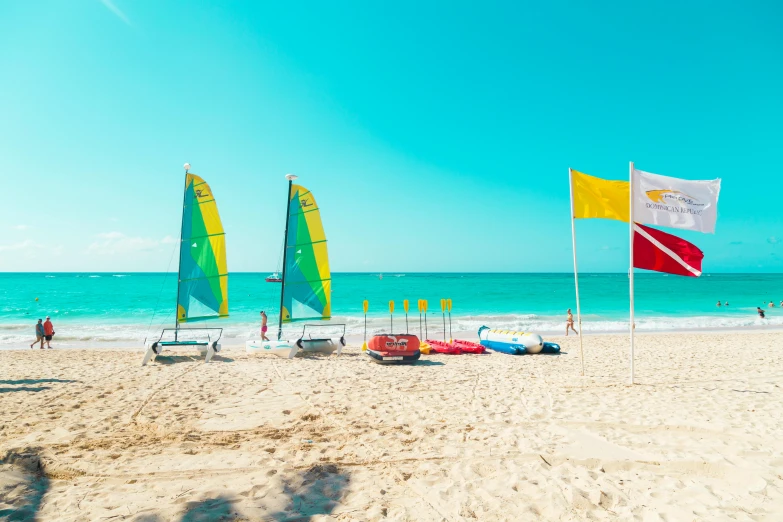 a group of sailboats sitting on top of a sandy beach, yellow theme, red flags holiday, aquamarine, instagram picture