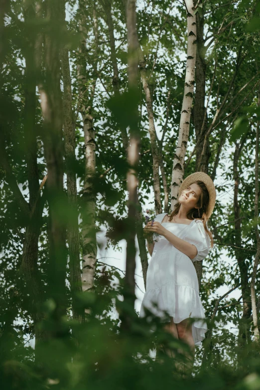 a woman in a white dress standing in a forest, pexels contest winner, woman with hat, climbing a tree, birch, lush and green