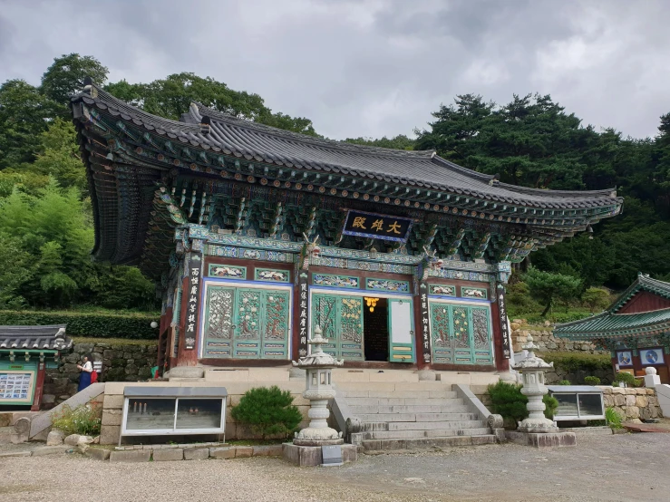 a large building sitting in the middle of a forest, inspired by Byeon Sang-byeok, unsplash, cloisonnism, in front of the temple, built on a steep hill, 3 doors, 2 0 0 0's photo