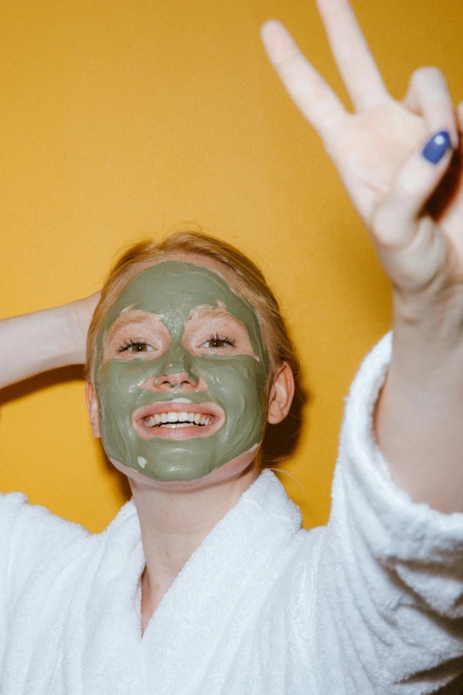 a woman putting a facial mask on her face, by Julia Pishtar, trending on pexels, sage green, everyone having fun, hard clay, snapchat photo