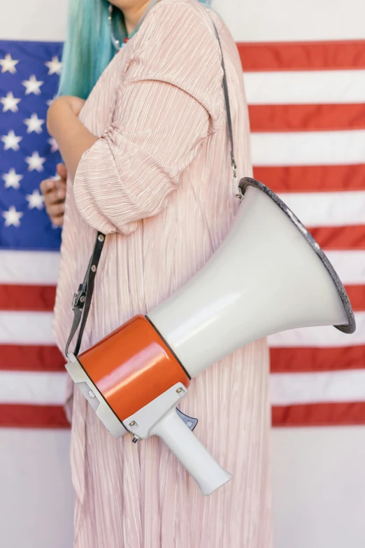 a woman with a megaphone in front of an american flag, a colorized photo, unsplash, maternal, 🚿🗝📝