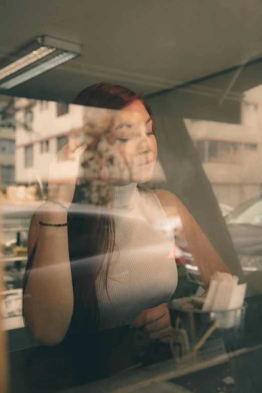 a woman sitting in a car talking on a cell phone, a picture, inspired by Elsa Bleda, pexels contest winner, sunshine through window, woman with red hair, mysterious coffee shop girl, reflections. shady